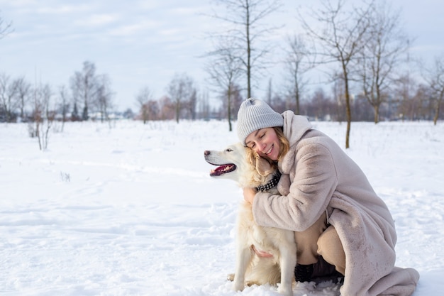 Giovane bella donna e il suo cane golden retriever che si divertono in inverno