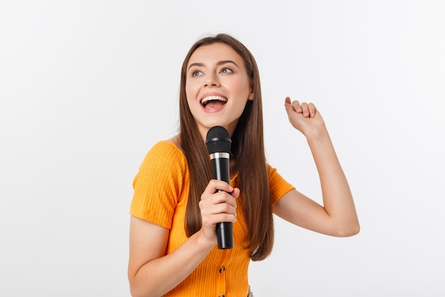 Giovane bella donna felice e motivata, cantando una canzone con un microfono, presentando un evento o una festa, goditi il momento