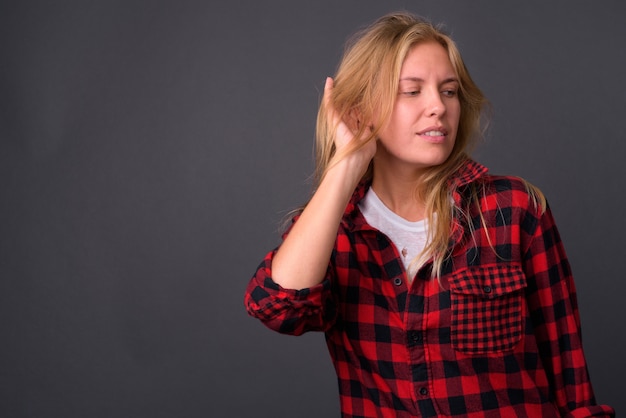 giovane bella donna hipster con capelli biondi contro il muro grigio