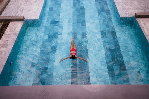 Giovane bella donna in bikini rosa, nuoto in piscina