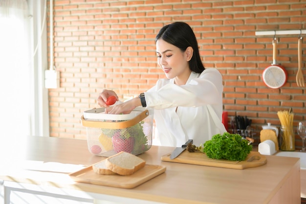 Giovane bella donna in camicia bianca che cucina in cucina