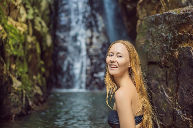 Giovane bella donna in piedi nell'acqua alla cascata