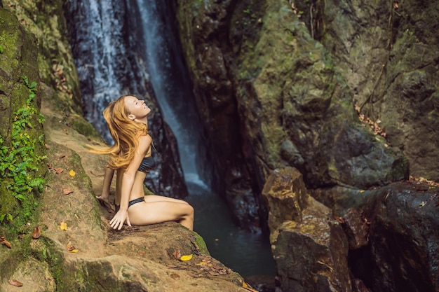 Giovane bella donna in piedi nell'acqua alla cascata