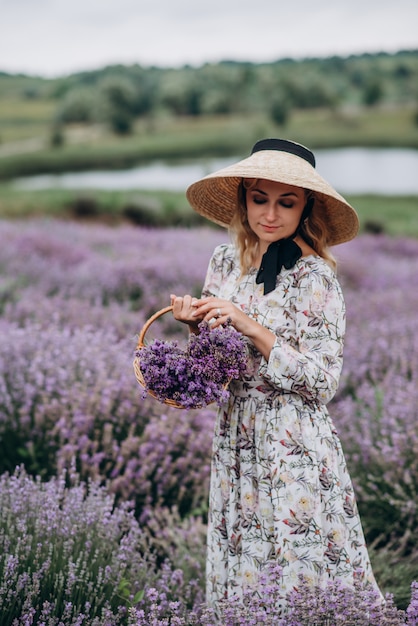 Giovane bella donna in un abito romantico nel campo di lavanda