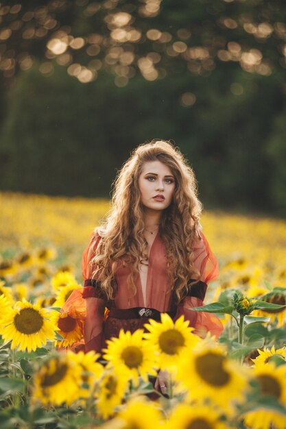 Giovane bella donna in un vestito tra i girasoli fioriti. Agro-cultura.