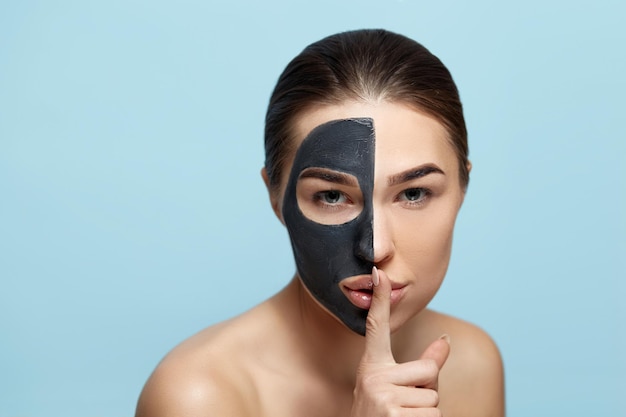 Giovane bella donna in una maschera per il viso di argilla nera Modalità ragazza Bellezza viso cura della pelle Spa