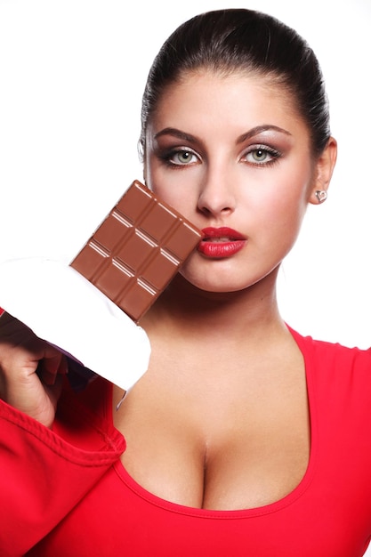 Giovane bella donna in vestito rosso che mangia cioccolato