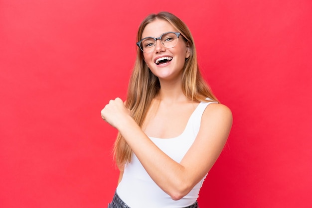 Giovane bella donna isolata su sfondo rosso che celebra una vittoria