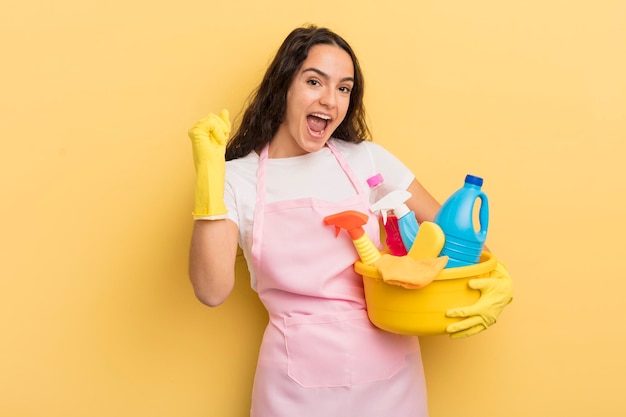 giovane bella donna ispanica che si sente scioccata, ride e celebra il successo. lavori domestici un concetto di prodotti puliti