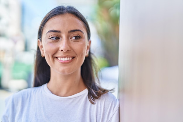 Giovane bella donna ispanica sorridente fiducioso guardando al lato della strada