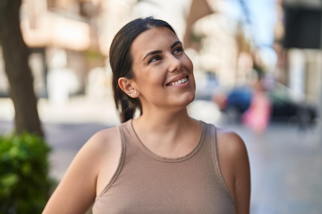 Giovane bella donna ispanica sorridente fiducioso guardando al lato della strada