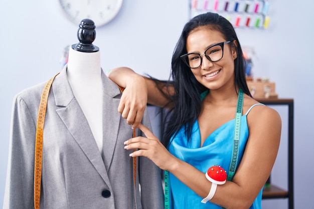 Giovane bella donna latina sarto sorridente fiducioso appoggiato sul manichino al fiorista