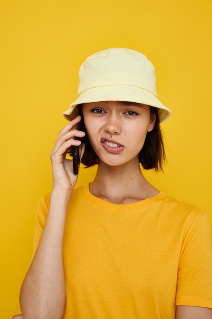 Giovane bella donna maglietta gialla e cappello stile estivo con telefono Stile di vita inalterato