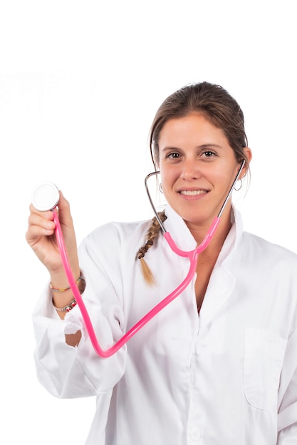 Giovane bella donna medico con stetoscopio rosa su fondo bianco.