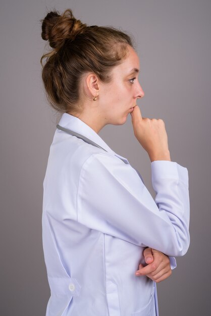 Giovane bella donna medico su sfondo grigio