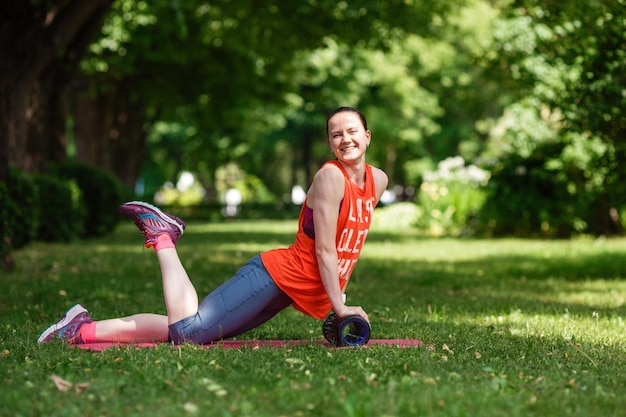 Giovane bella donna medita in una giornata estiva nel parco Idea e concetto di calma in una città frenetica e uno stile di vita sano che si allunga e si prepara per una corsa nel parco