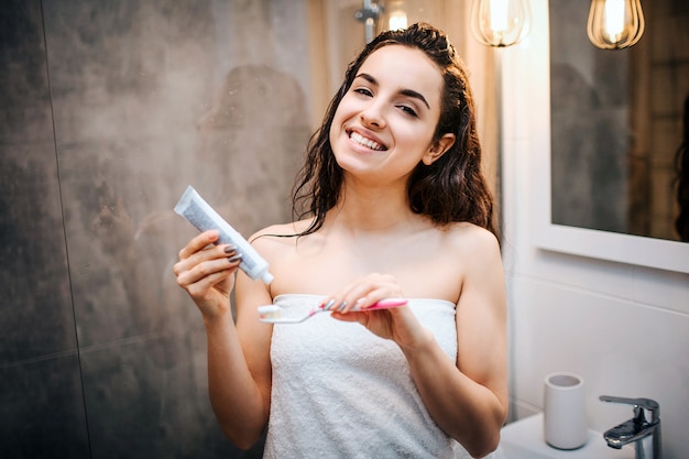 Giovane bella donna mora sportiva che fa la routine di sera di mattina allo specchio.