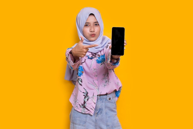 Giovane bella donna musulmana asiatica che dimostra telefono cellulare mobile isolato su sfondo bianco