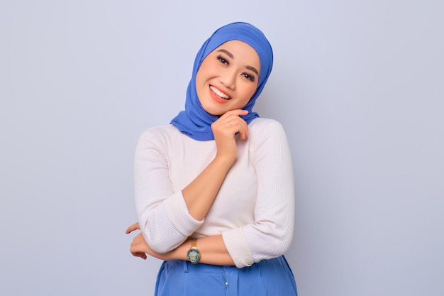 Giovane bella donna musulmana asiatica che si sente sicura e sorridente felice isolata sopra priorità bassa bianca