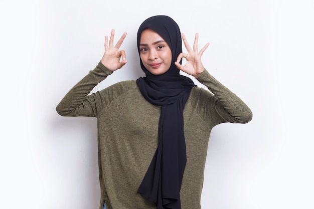 Giovane bella donna musulmana asiatica con gesto di segno ok tumb up isolato su sfondo bianco