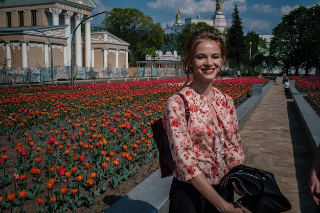 Giovane bella donna nel campo di tulipani Concetto di moda primaverile Naturalezza nello stile una passeggiata nel parco L'idea e il concetto di donne felici nella Giornata internazionale della donna