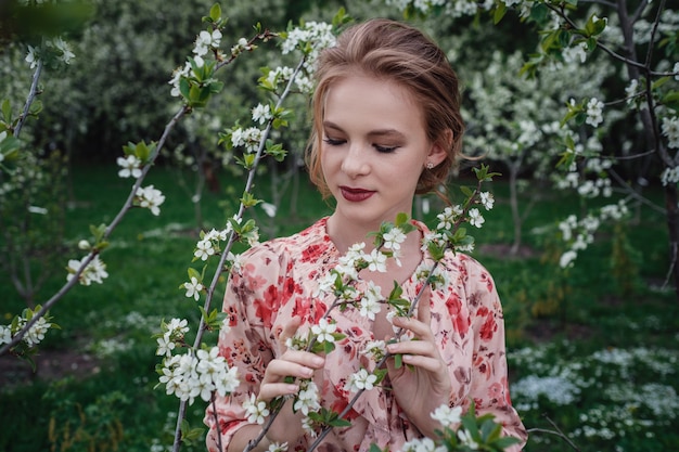 Giovane bella donna nel giardino di fiori di ciliegio.