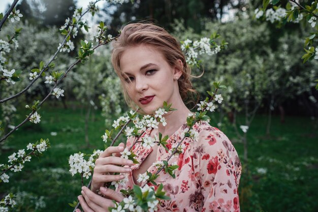 Giovane bella donna nel giardino di fiori di ciliegio.