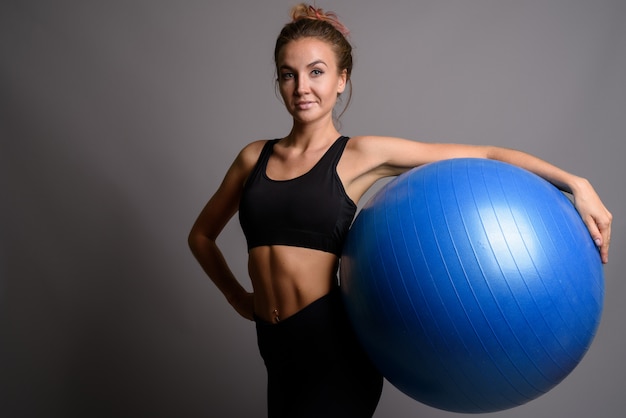 Giovane bella donna pronta per la palestra contro la parete grigia