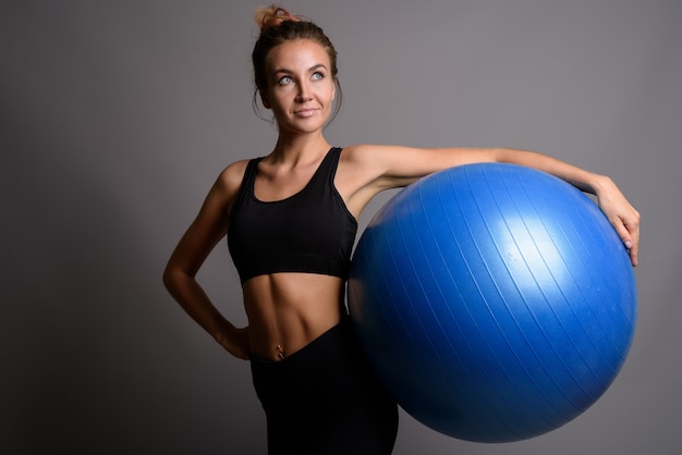 Giovane bella donna pronta per la palestra contro la parete grigia