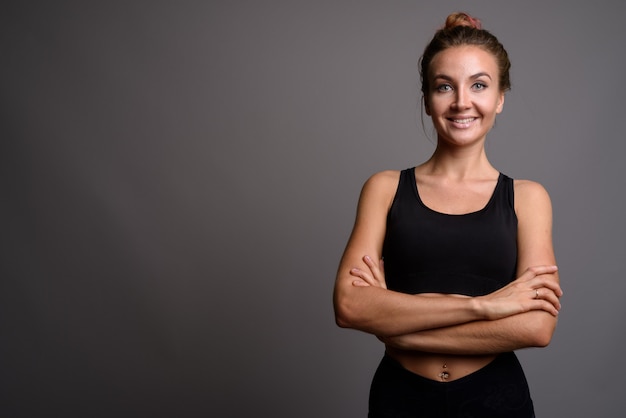 Giovane bella donna pronta per la palestra contro la parete grigia