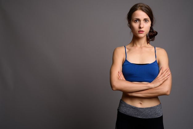 Giovane bella donna pronta per la palestra contro la parete grigia