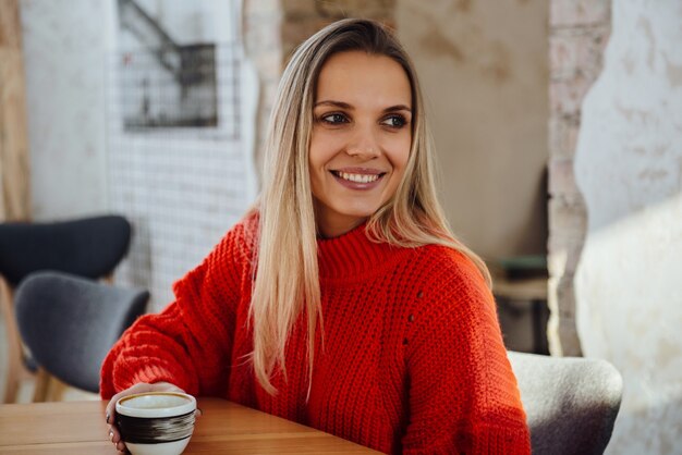 Giovane bella donna seduta in un bar con un caffè