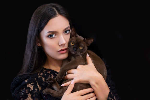Giovane bella donna sexy con trucco luminoso con un gatto in mano