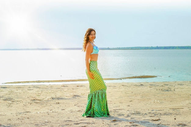 Giovane bella donna sirena da vicino in piedi sul costo del mare con la luce del sole. Sirena cosplay