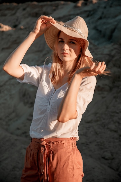 Giovane bella donna sola con i capelli lunghi con cappello di paglia. Una ragazza sola scende le dune di sabbia.