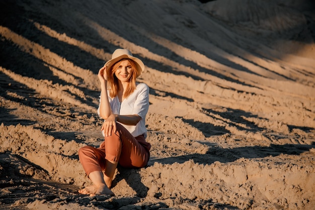 Giovane bella donna sola con i capelli lunghi con cappello di paglia. Una ragazza sola scende le dune di sabbia.