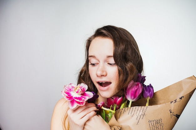 Giovane bella donna sorpresa che tiene un mazzo di fiori, celebrando la Giornata mondiale della donna l'8 marzo March