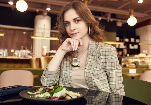 Giovane bella donna sorridente che mangia alimento sano