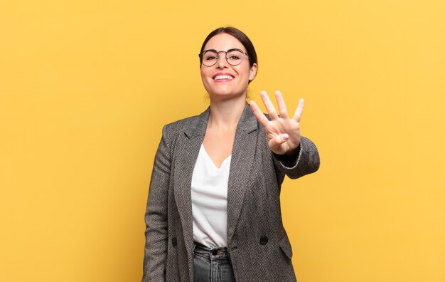 Giovane bella donna sorridente e dall'aspetto amichevole, mostrando il numero quattro o il quarto con la mano in avanti, conto alla rovescia