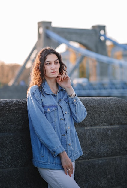 Giovane bella donna sorridente hipster in abiti estivi alla moda Modello spensierato sexy in posa sullo sfondo della strada Europa al tramonto Femmina bruna positiva Allegro e felice