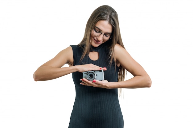 Giovane bella donna sorridente in occhiali vestito nero tenendo la macchina fotografica in mano