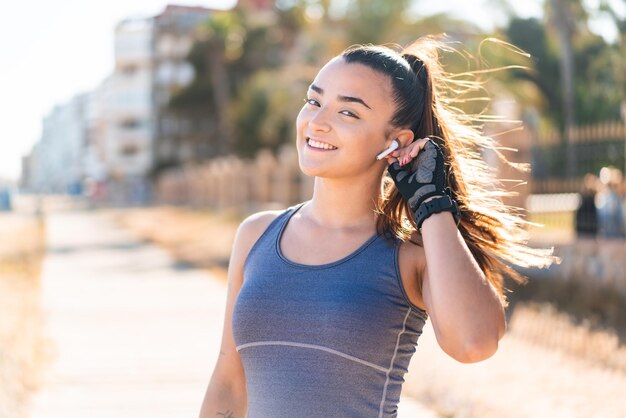 Giovane bella donna sportiva che indossa abbigliamento sportivo e musica d'ascolto con cuffie wireless