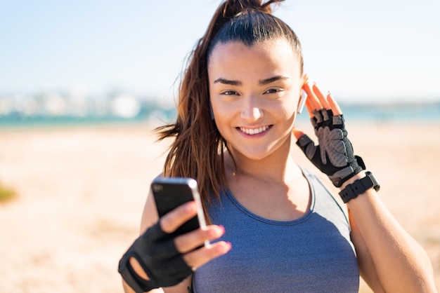 Giovane bella donna sportiva che indossa abbigliamento sportivo e musica d'ascolto con il telefono