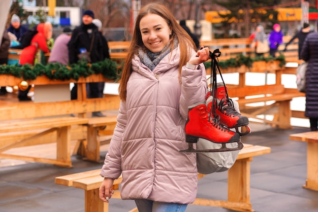 giovane bella donna su una pista di pattinaggio con i pattini in mano