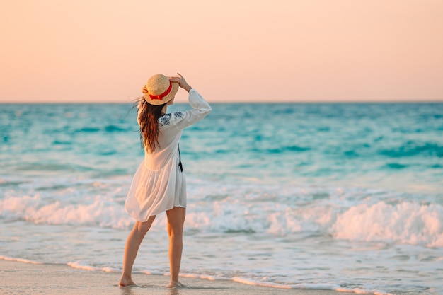 Giovane bella donna sulla spiaggia tropicale nel tramonto.