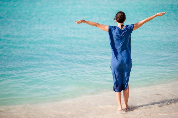 Giovane bella donna sulla spiaggia tropicale. Ragazza felice che si distende alla spiaggia tropicale della sabbia bianca