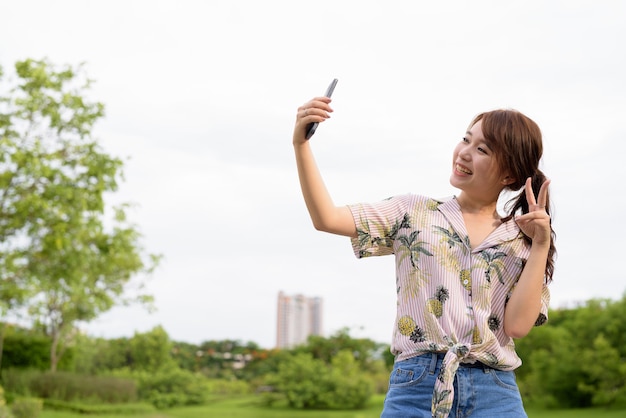 Giovane bella donna turistica asiatica che si distende al parco