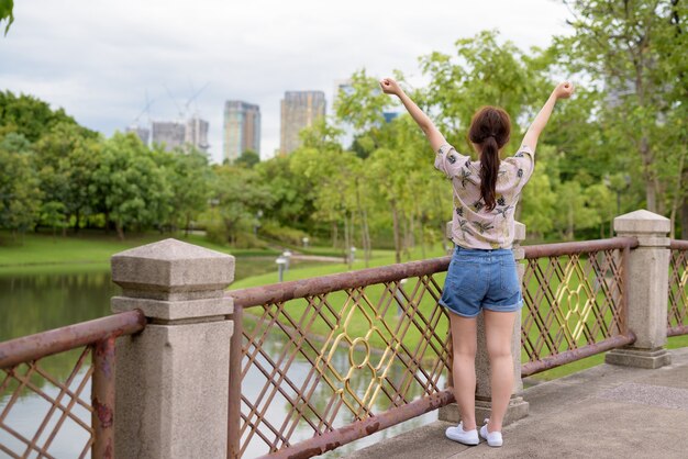 Giovane bella donna turistica asiatica che si distende al parco