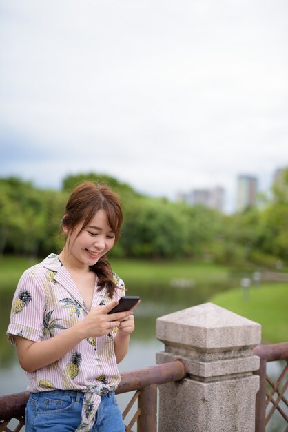 Giovane bella donna turistica asiatica che si distende al parco