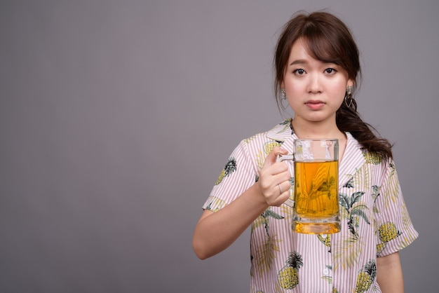Giovane bella donna turistica asiatica che tiene un bicchiere di birra